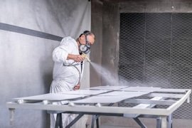 A KRS finisher spraying panels in the paint booth