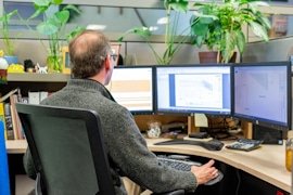 A KRS engineer working on fixture drawings across three monitors
